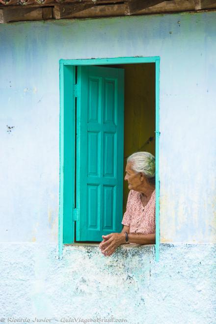 Imagem de uma senhora na janela de sua casa em um vilarejo em Caraiva.